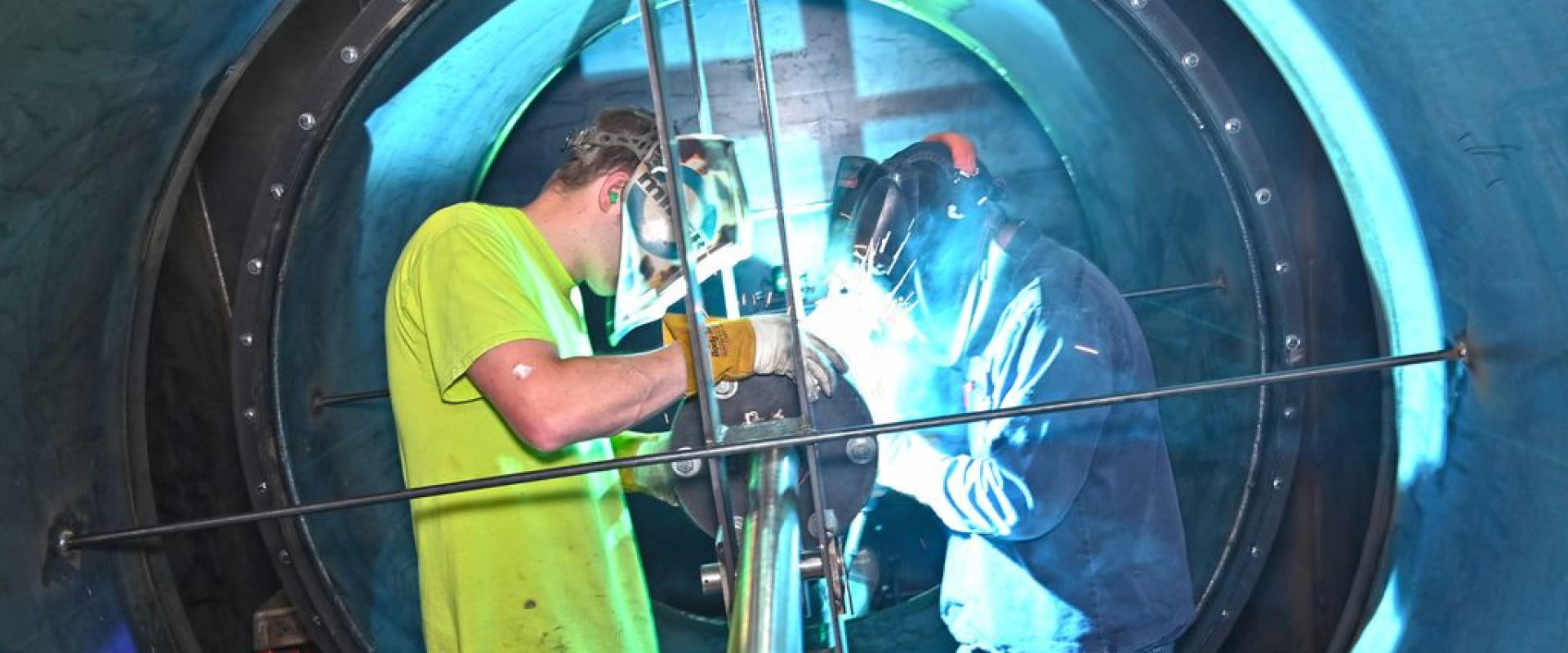 Two TANN employees grinding on a large metal tube